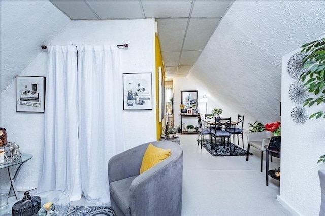 interior space with a paneled ceiling, vaulted ceiling, and concrete flooring