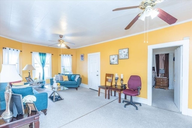 carpeted living area with ornamental molding, ceiling fan, and baseboards