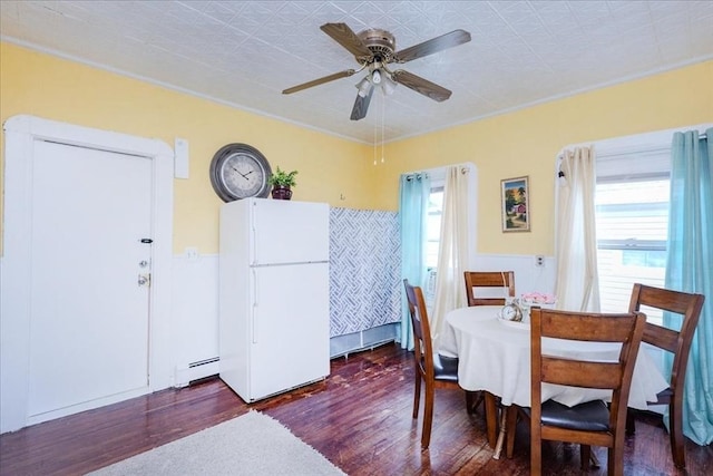 dining space with a wainscoted wall, ceiling fan, baseboard heating, and wood finished floors