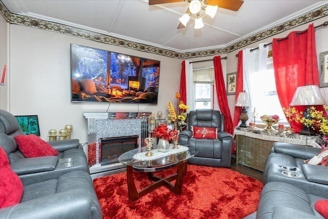 living room featuring a glass covered fireplace, wood finished floors, crown molding, and ceiling fan