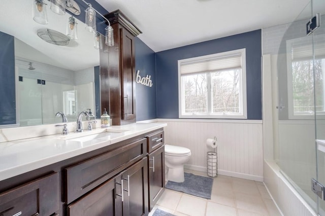 full bathroom featuring a healthy amount of sunlight, tile patterned flooring, a shower, a wainscoted wall, and toilet
