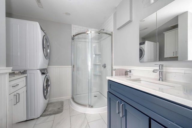 bathroom with stacked washer and dryer, wainscoting, vanity, visible vents, and a stall shower