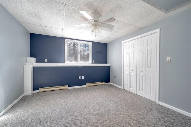 unfurnished bedroom featuring carpet flooring, a paneled ceiling, and a baseboard heating unit