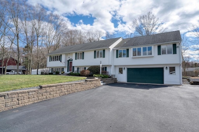 raised ranch featuring an attached garage, driveway, and a front lawn