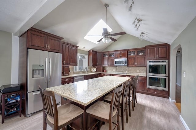 kitchen with a sink, a ceiling fan, stainless steel appliances, and light wood-type flooring