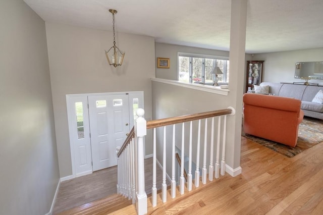 foyer featuring baseboards, wood finished floors, and a notable chandelier