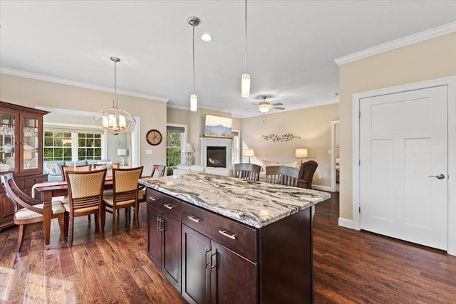 kitchen with pendant lighting, dark hardwood / wood-style flooring, light stone countertops, and crown molding