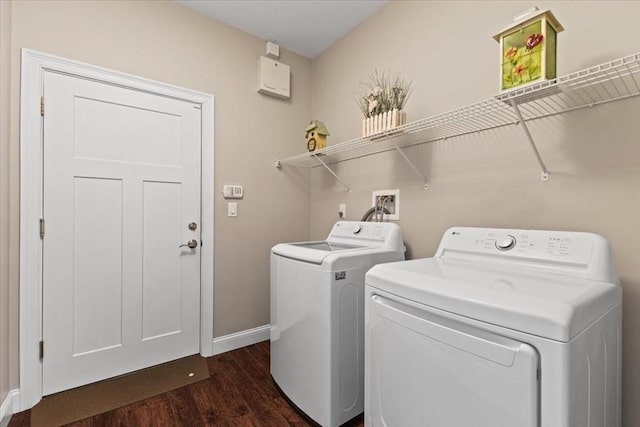 clothes washing area featuring washing machine and clothes dryer and dark hardwood / wood-style floors