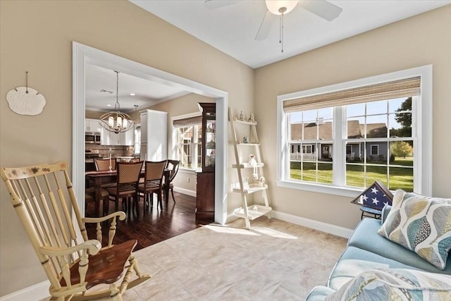 living area with ceiling fan with notable chandelier, plenty of natural light, and wood-type flooring