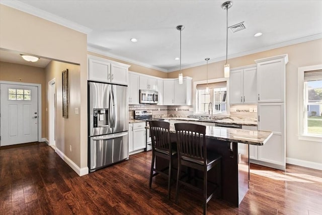 kitchen featuring stainless steel appliances, hanging light fixtures, a center island, and white cabinets