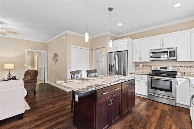 kitchen with a breakfast bar, appliances with stainless steel finishes, hanging light fixtures, tasteful backsplash, and a kitchen island