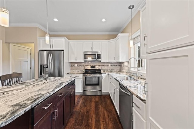 kitchen featuring appliances with stainless steel finishes, sink, white cabinets, and decorative light fixtures