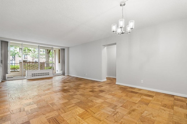 99 Pond Ave Unit 220, Brookline, MA 02445 - spare room with a chandelier, a textured ceiling, a wall of windows, and radiator heating unit