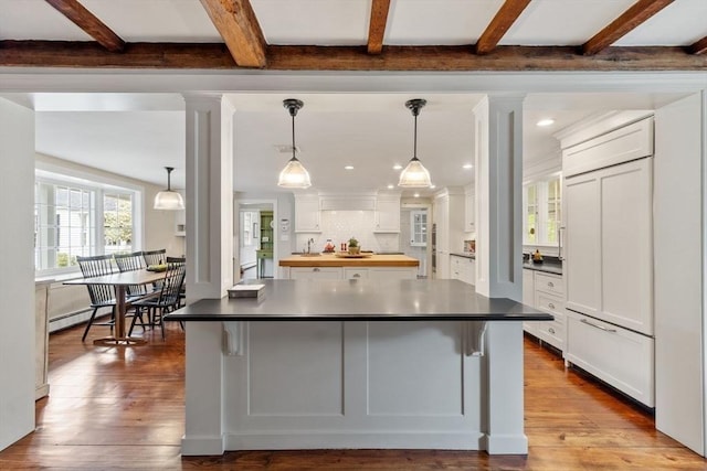 894 Great Pond Rd, North Andover, MA 01845 - kitchen with beamed ceiling, white cabinetry, wood-type flooring, baseboard heating, and a breakfast bar