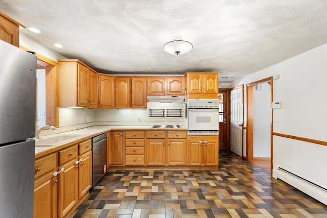 kitchen featuring stainless steel appliances, a sink, baseboard heating, light countertops, and under cabinet range hood