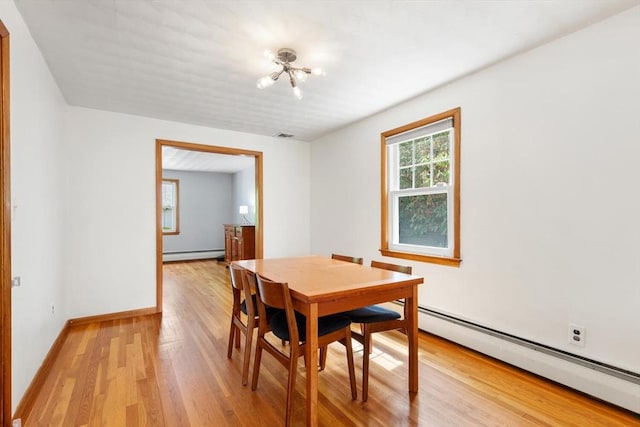 dining area featuring baseboard heating, a baseboard heating unit, a chandelier, light wood finished floors, and baseboards
