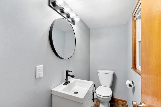 half bathroom with toilet, vanity, and baseboards