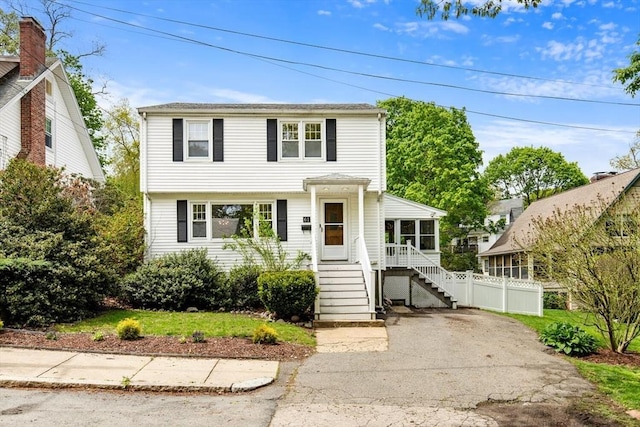 view of front of property featuring a sunroom, stairway, and fence