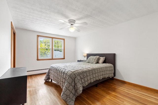 bedroom featuring a baseboard radiator, wood finished floors, a ceiling fan, and a textured ceiling