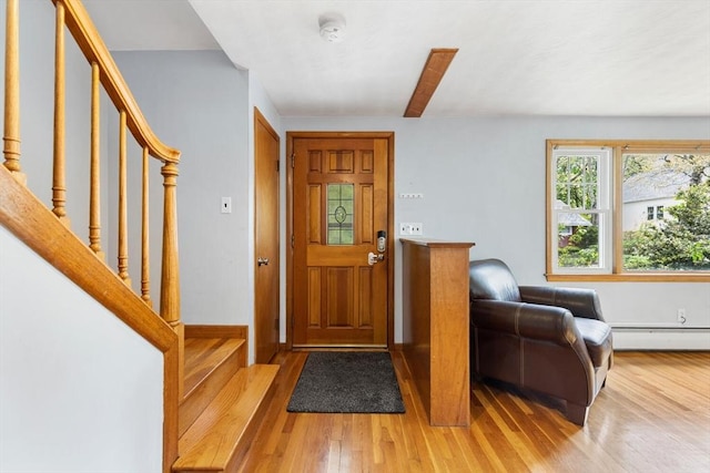 foyer entrance featuring wood finished floors, a baseboard heating unit, stairs, and baseboards