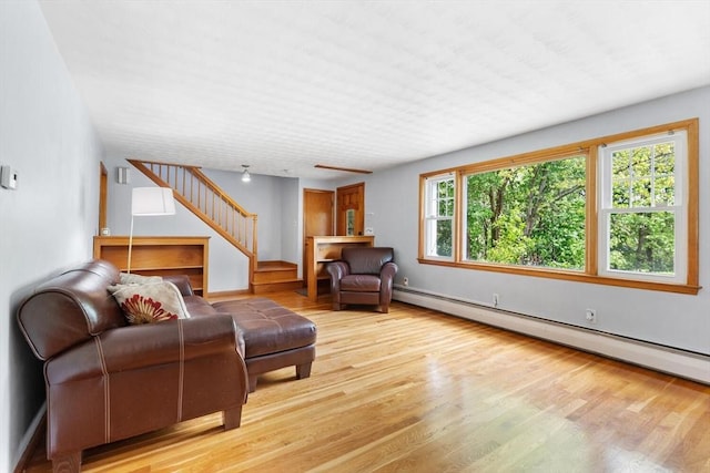 living room featuring a baseboard heating unit, stairway, and wood finished floors
