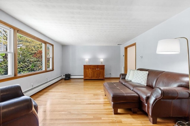 living area with baseboard heating, light wood-type flooring, and baseboards