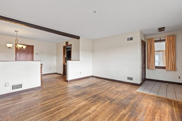 empty room with an inviting chandelier, dark wood-type flooring, and beamed ceiling