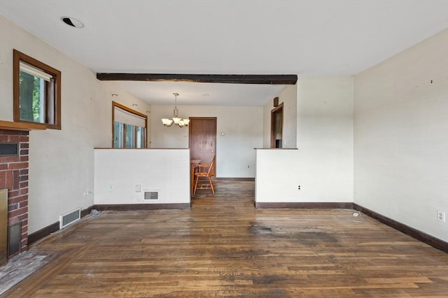 unfurnished living room featuring beam ceiling, a brick fireplace, dark hardwood / wood-style floors, and an inviting chandelier