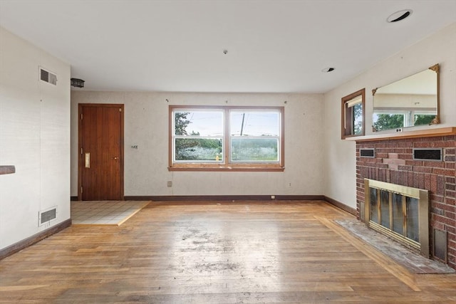 unfurnished living room featuring a brick fireplace and light hardwood / wood-style floors