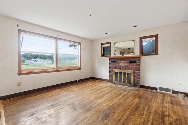 unfurnished living room with hardwood / wood-style floors and a brick fireplace