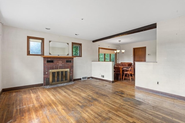 unfurnished living room with beam ceiling, a brick fireplace, hardwood / wood-style flooring, and plenty of natural light