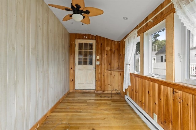 unfurnished sunroom featuring a baseboard heating unit, vaulted ceiling, and ceiling fan