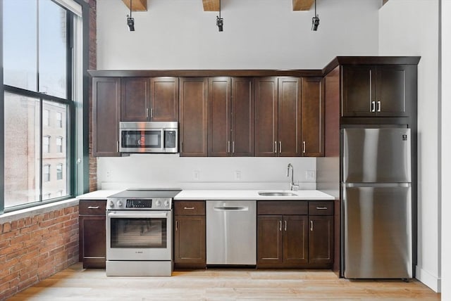 49 Melcher St Unit 405, Boston, MA 02110 - kitchen featuring stainless steel appliances, plenty of natural light, a sink, brick wall, and dark brown cabinetry