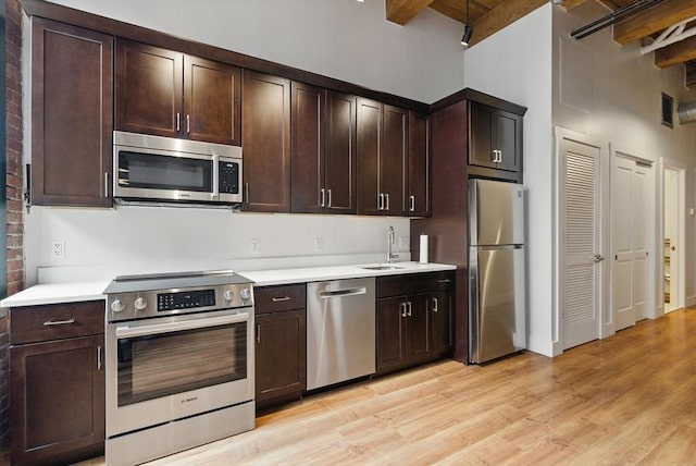 49 Melcher St Unit 405, Boston, MA 02110 - kitchen with appliances with stainless steel finishes, light wood finished floors, light countertops, beamed ceiling, and a sink