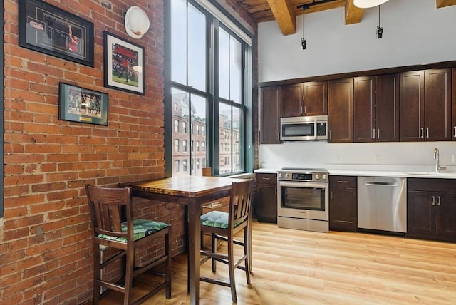49 Melcher St Unit 405, Boston, MA 02110 - kitchen with stainless steel appliances, beamed ceiling, a sink, light wood finished floors, and dark brown cabinetry