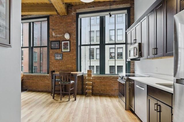 49 Melcher St Unit 405, Boston, MA 02110 - kitchen with stainless steel appliances, brick wall, light wood-type flooring, light countertops, and dark brown cabinetry