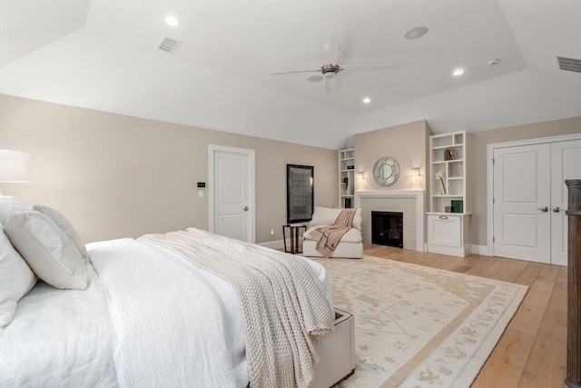 bedroom featuring a fireplace, lofted ceiling, recessed lighting, visible vents, and light wood-type flooring