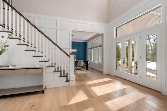 entrance foyer featuring light wood-type flooring, a decorative wall, and stairway