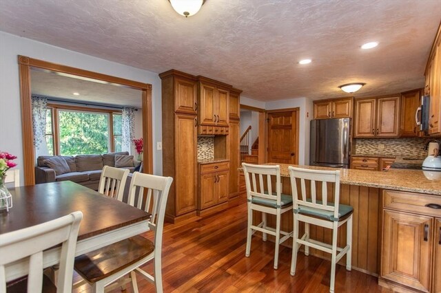 kitchen with dark hardwood / wood-style floors, tasteful backsplash, light stone countertops, and appliances with stainless steel finishes