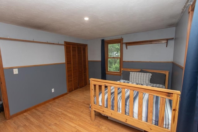 bedroom with multiple windows, baseboard heating, and light hardwood / wood-style floors