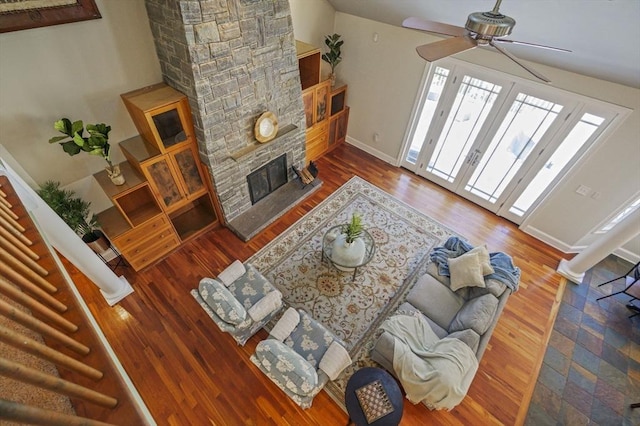 living room with hardwood / wood-style floors, a stone fireplace, and ceiling fan