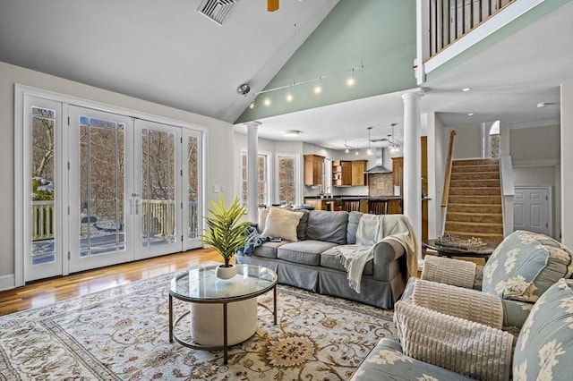 living room with ceiling fan, high vaulted ceiling, ornate columns, french doors, and light wood-type flooring