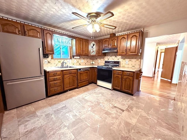 333 Clark Rd, Lowell, MA 01852 - kitchen featuring freestanding refrigerator, range with gas cooktop, under cabinet range hood, a sink, and light countertops
