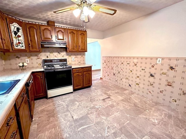 333 Clark Rd, Lowell, MA 01852 - kitchen featuring gas stove, ceiling fan, light countertops, under cabinet range hood, and brown cabinets