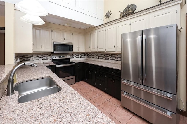 kitchen featuring white cabinetry, sink, tasteful backsplash, light tile patterned floors, and appliances with stainless steel finishes