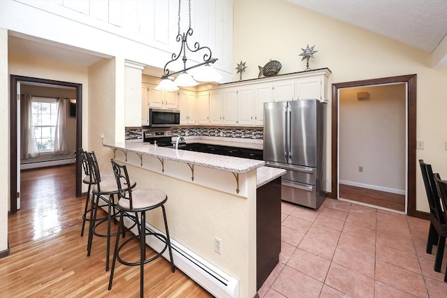 kitchen featuring pendant lighting, a breakfast bar, tasteful backsplash, kitchen peninsula, and stainless steel appliances