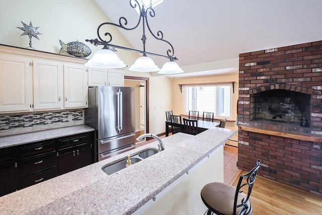 kitchen with white cabinets, high end refrigerator, light stone counters, and sink