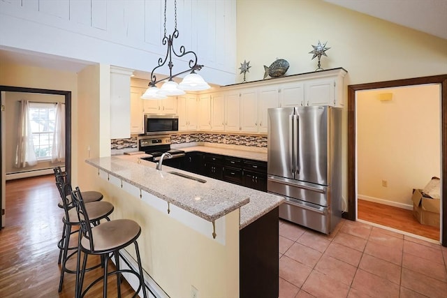 kitchen with pendant lighting, sink, appliances with stainless steel finishes, light stone counters, and white cabinetry