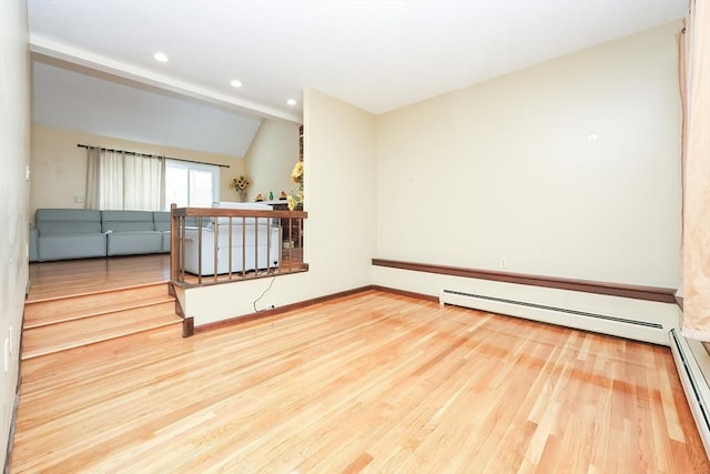 unfurnished room with lofted ceiling, hardwood / wood-style flooring, and a baseboard heating unit