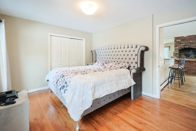 bedroom featuring a closet, wood-type flooring, and a brick fireplace